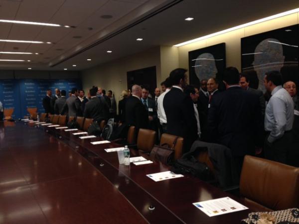 People standing to one side of a conference table socializing