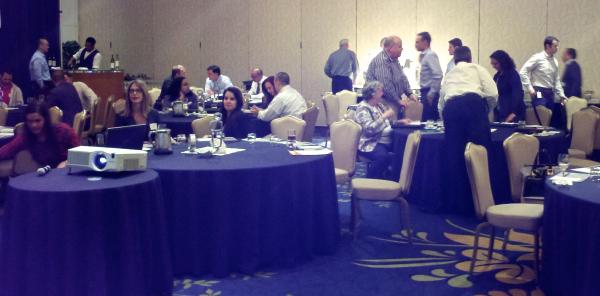 People socializing - some standing, some sitting at large round tables
