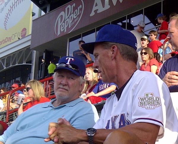 2 men sitting and talking together in the stands