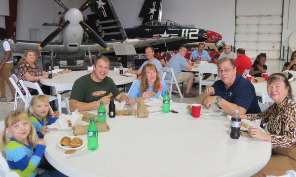 Attendees sitting at round table eating, planes in background