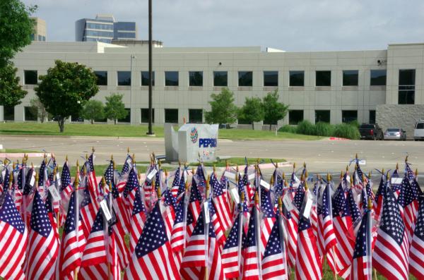 hundreds of american flags in foreground, Pepsico company sign and building in background