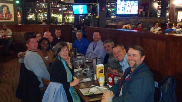 Group of people sitting around a table in the restaurant posing for the photo